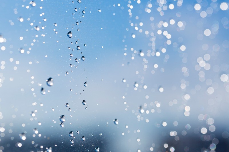Gocce d'acqua su vetro con sfondo blu.