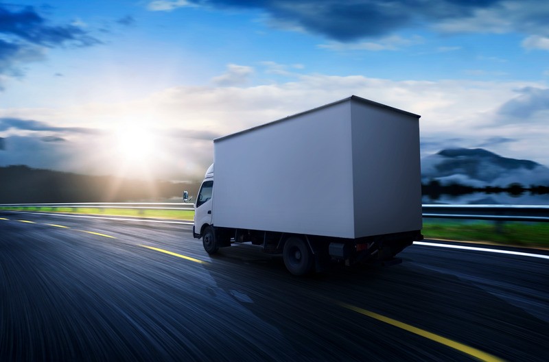 Camion bianco su strada al tramonto.