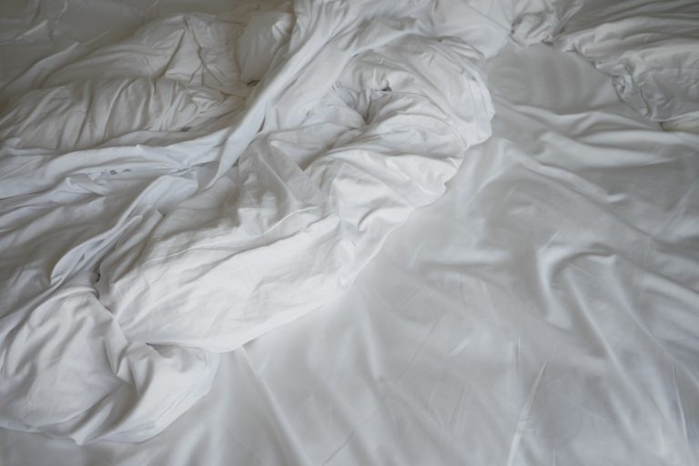 Lenzuola bianche stropicciate su un letto.